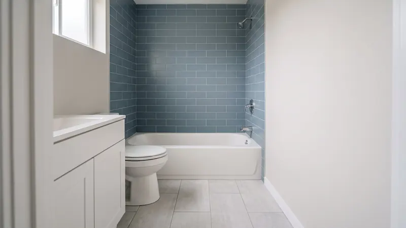 Design rendering of a hall bathroom with new blue gray tile around a white tub, new light gray floor tile, and the toilet and vanity in their usual places