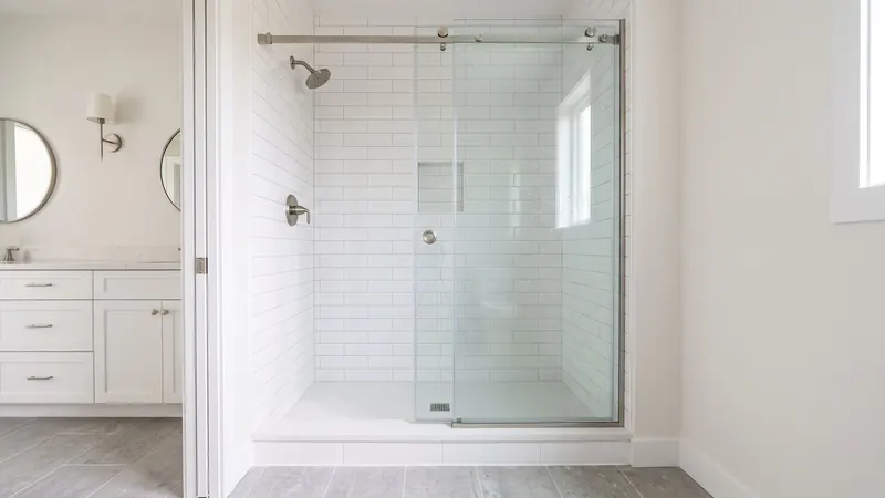 Design rendering of a shower with a semi-frameless sliding glass door, brushed nickel hardware and white wall tile
